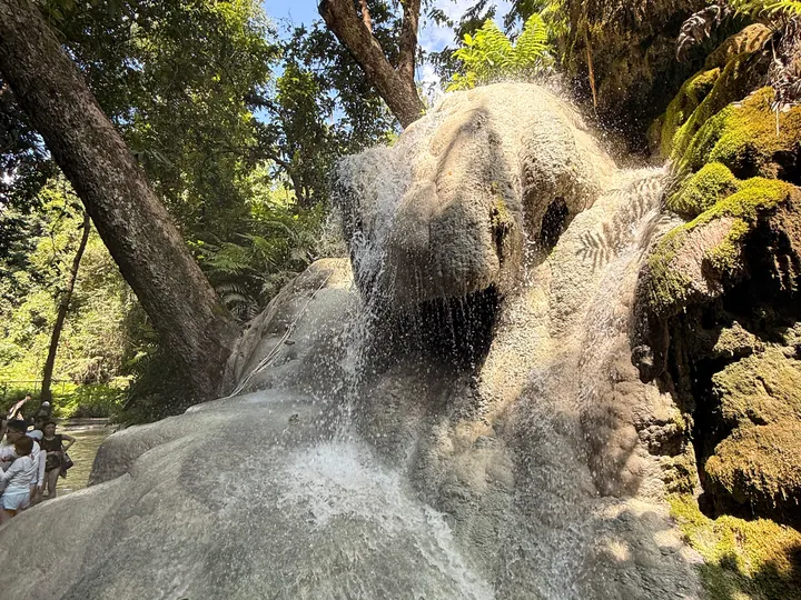 Water flowing over coarse pale rock, with moss beside the main channel.