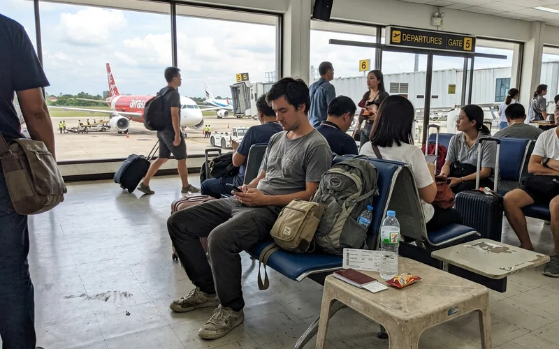 A traveller with a backpack at a Chiang Mai airport departure gate