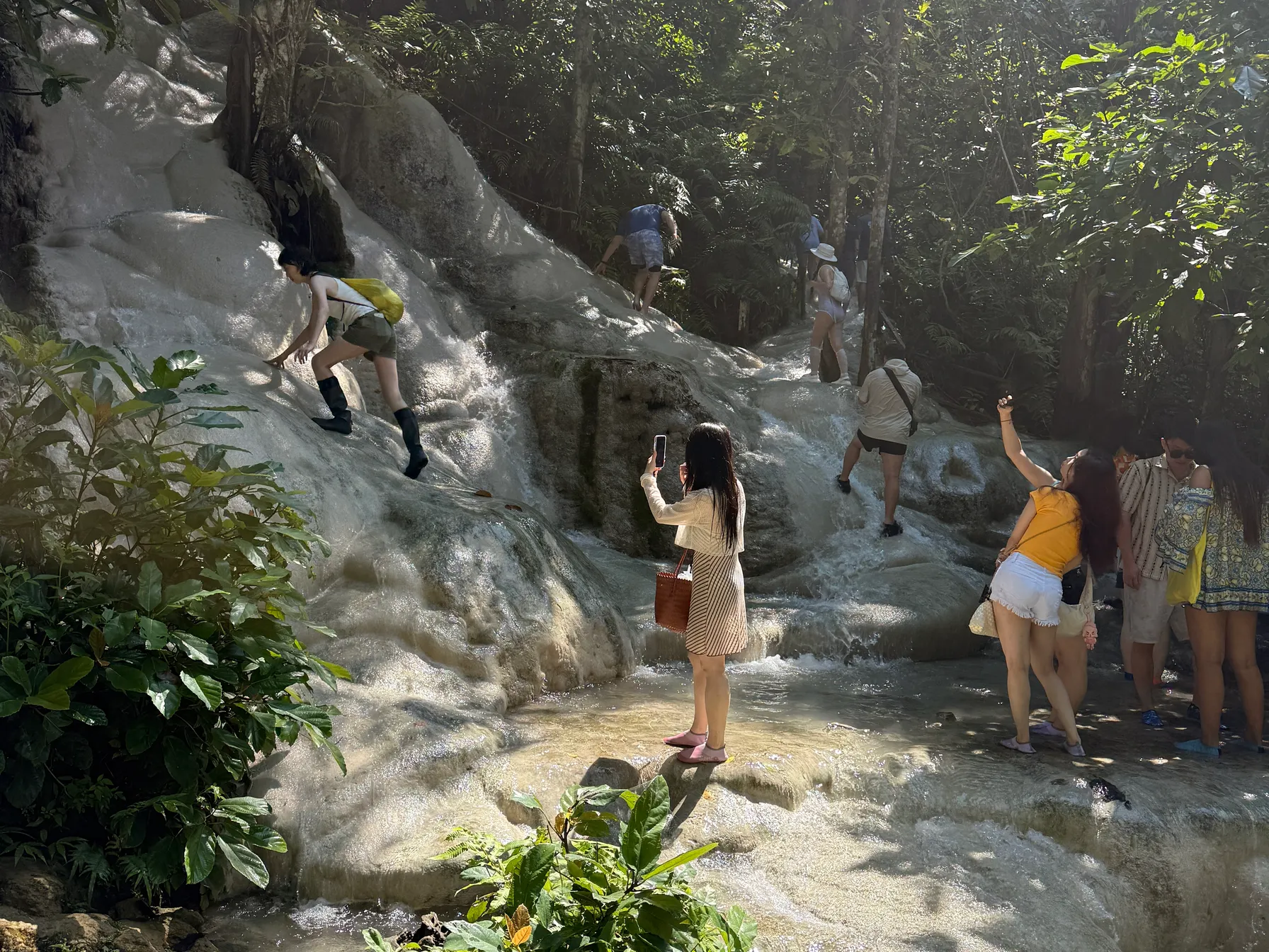Visitors on the pale cascades while water runs over the rock.