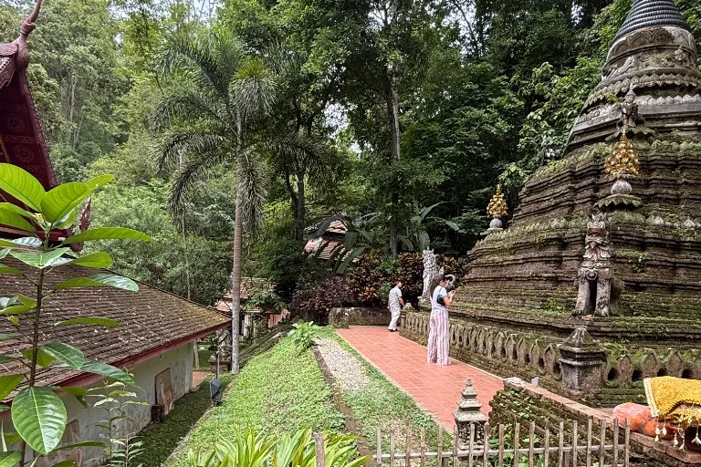 Stone chedi and temple buildings at Wat Pha Lat among forest trees on Doi Suthep.
