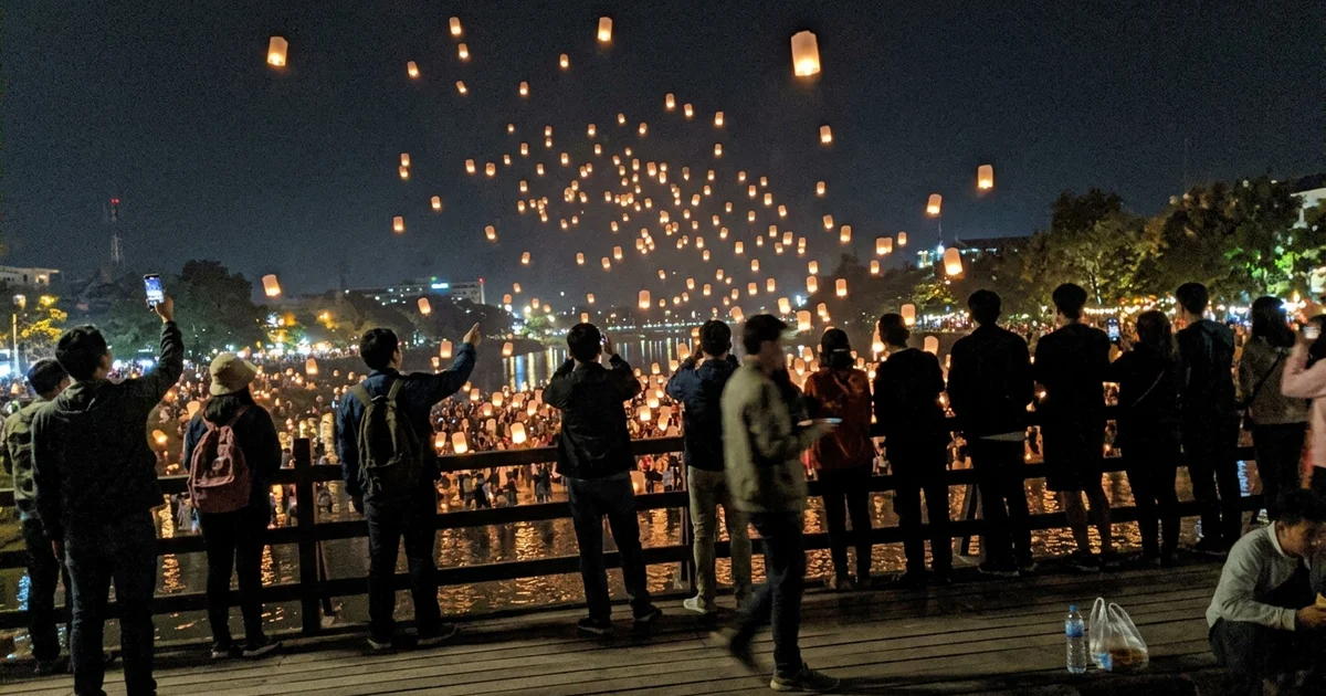 Paper lanterns drifting up over Chiang Mai at night during Yi Peng