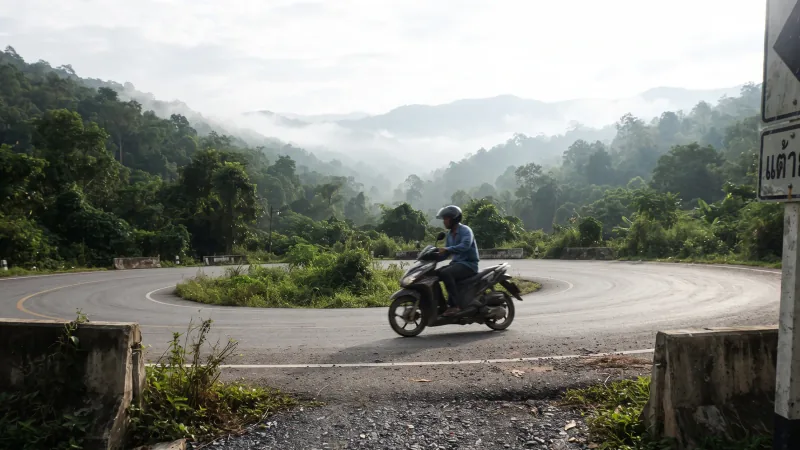 Mountain road curving through forested hills north of Chiang Mai in the cool season