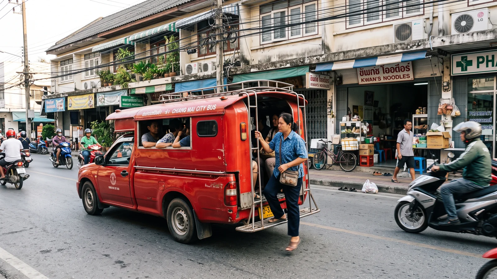 A red songthaew picking up passengers on a Chiang Mai street